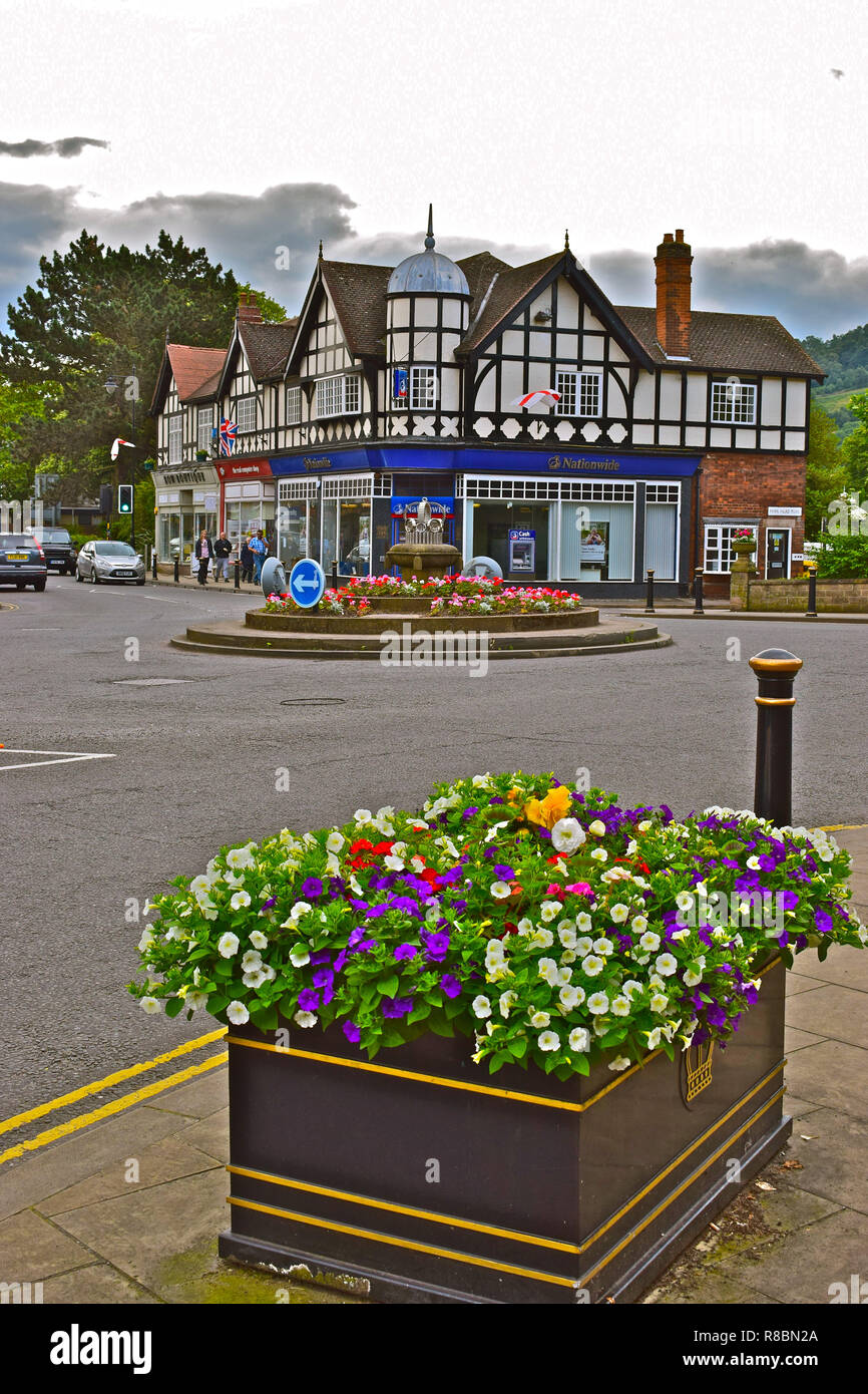 Pretty floral displays and an attractive old building occupied by the Nationwide Building Society,  enhance this street view of Matlock town centre. Stock Photo