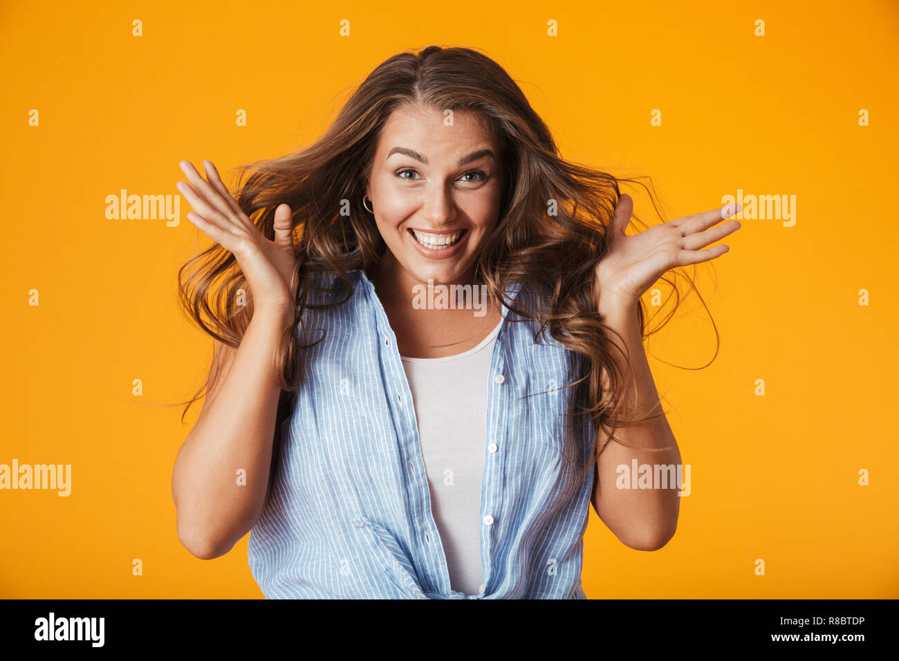 Excited young woman standing isolated over yellow background, celebrating success Stock Photo