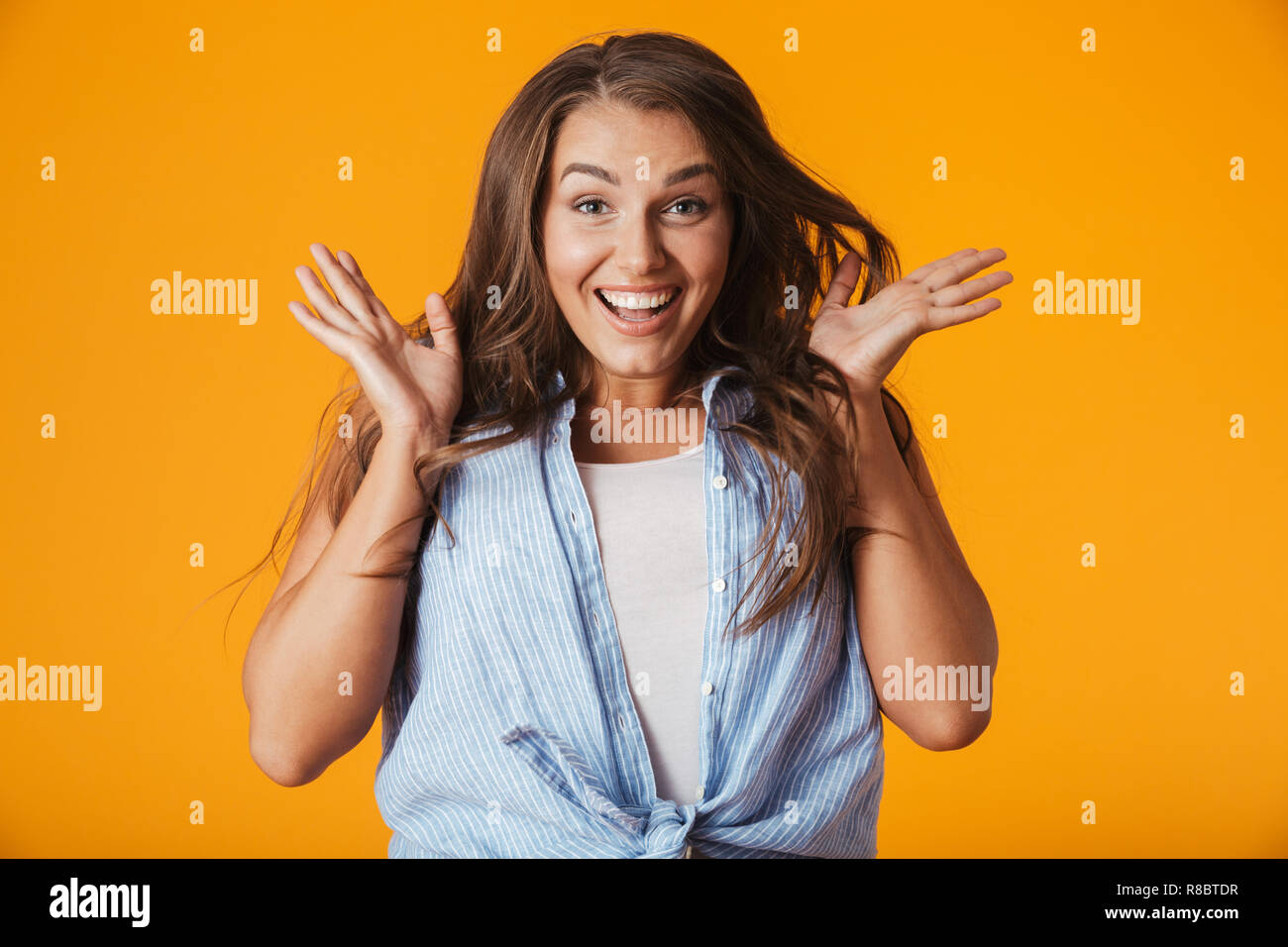 Excited young woman standing isolated over yellow background, celebrating success Stock Photo