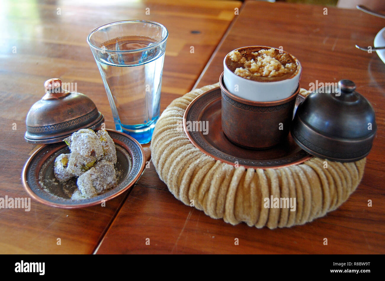 Turkish coffee with hazelnut served in a cup covered by a copper lid and set on a soft cupholder resembling a pasha hat. Stock Photo