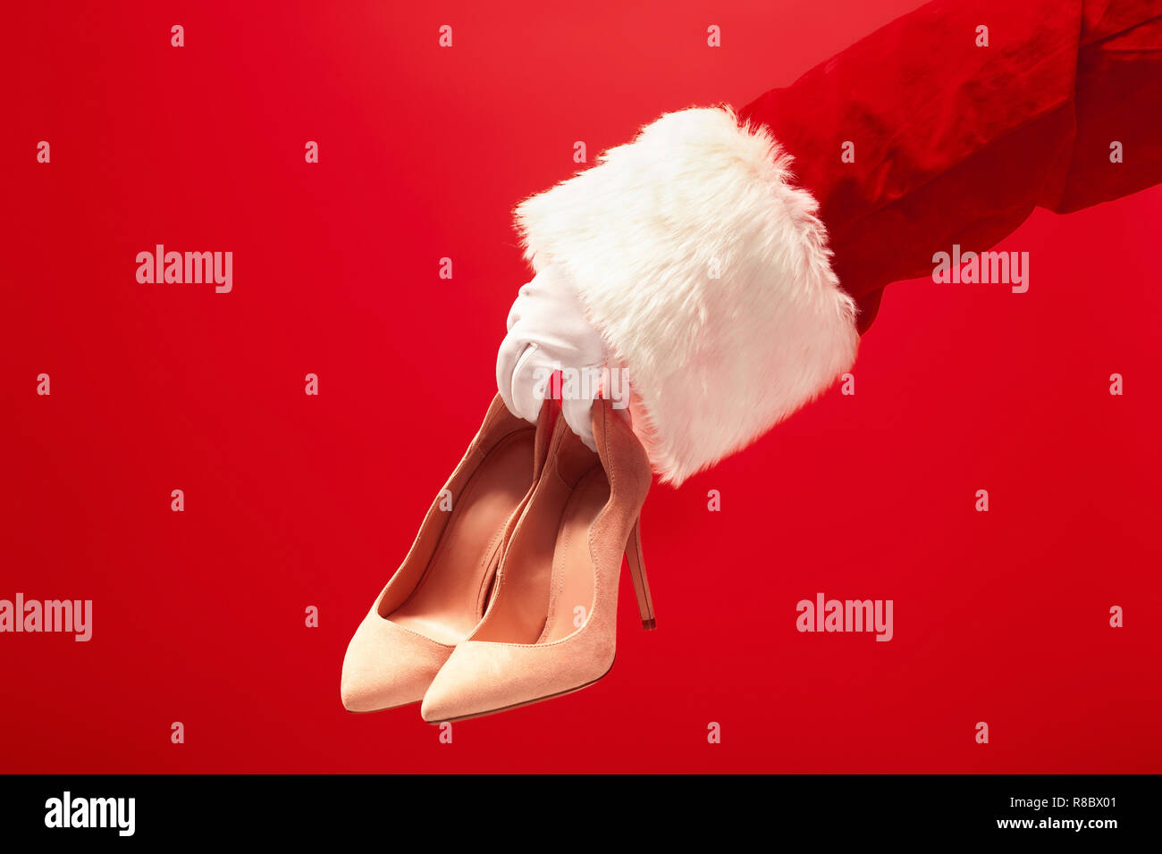 The Hand Of Santa Claus Holding A Women S Shoes On Red Background
