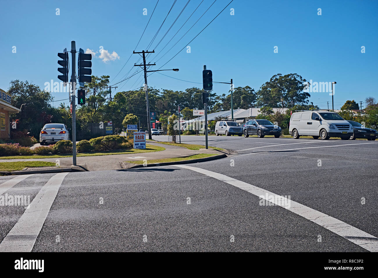 Traffic waiting at a junction on a road while the pedestrian crossing symbol shows green, Toormina, New South Wales, Australia Stock Photo