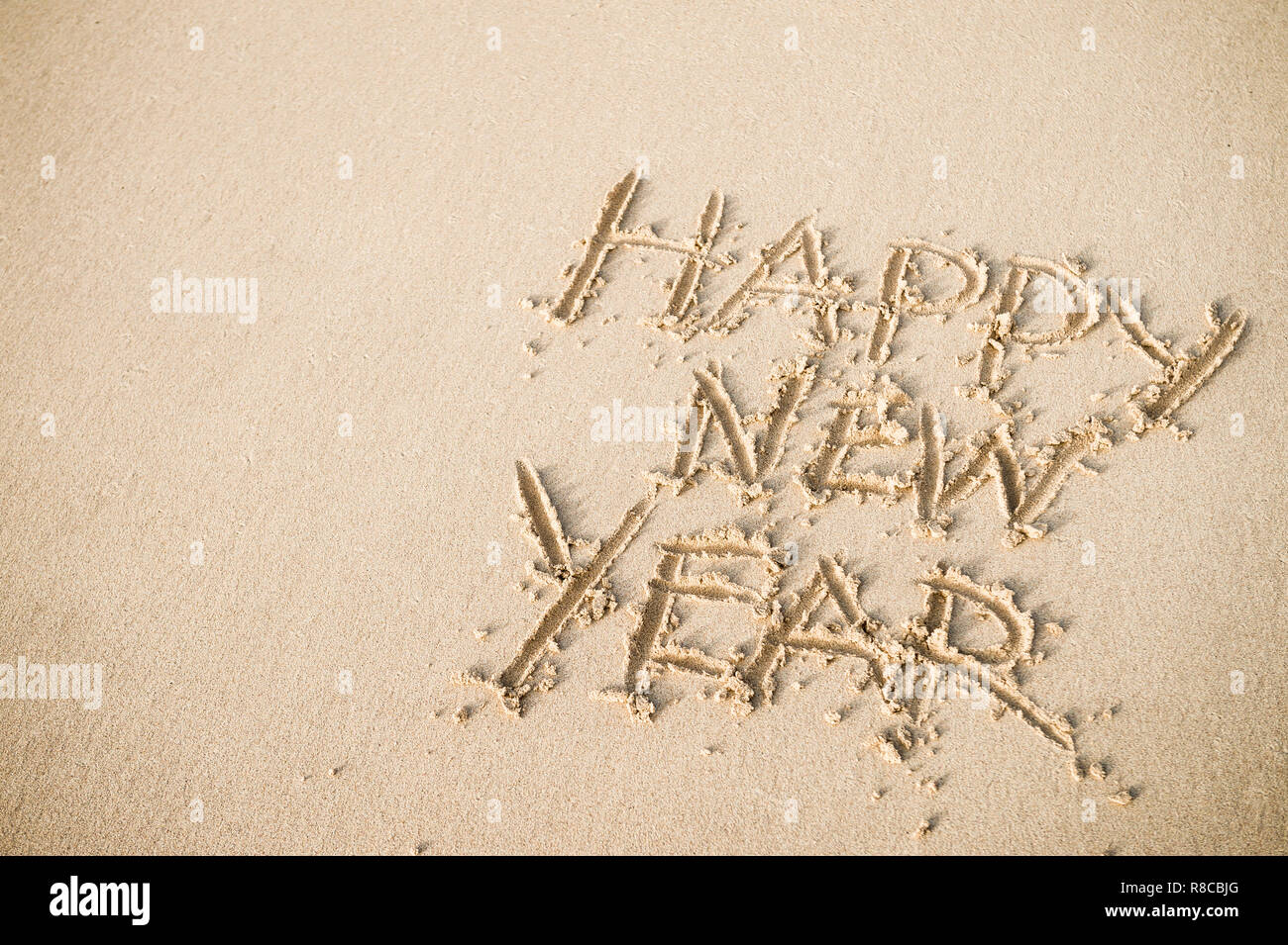 Happy New Year message handwritten on smooth sand beach Stock Photo