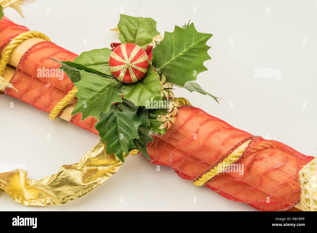 Pieces of cane adorned with red cloth, golden string and leaves with Christmas motifs. Stock Photo