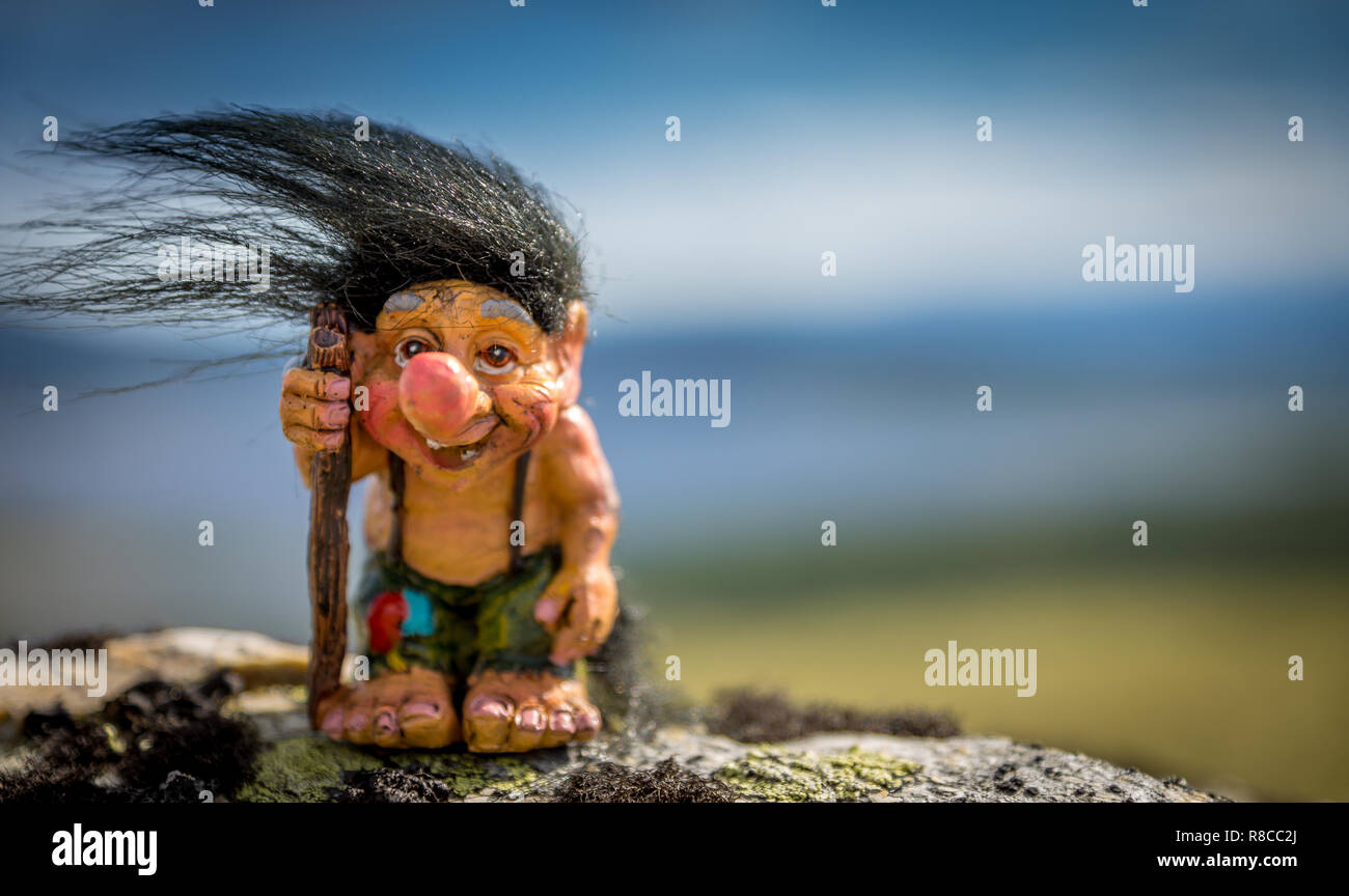 Happy troll out in the nature with his walking stick and black hair. Hair, hike, nature, wilderness, camping concept. Stock Photo