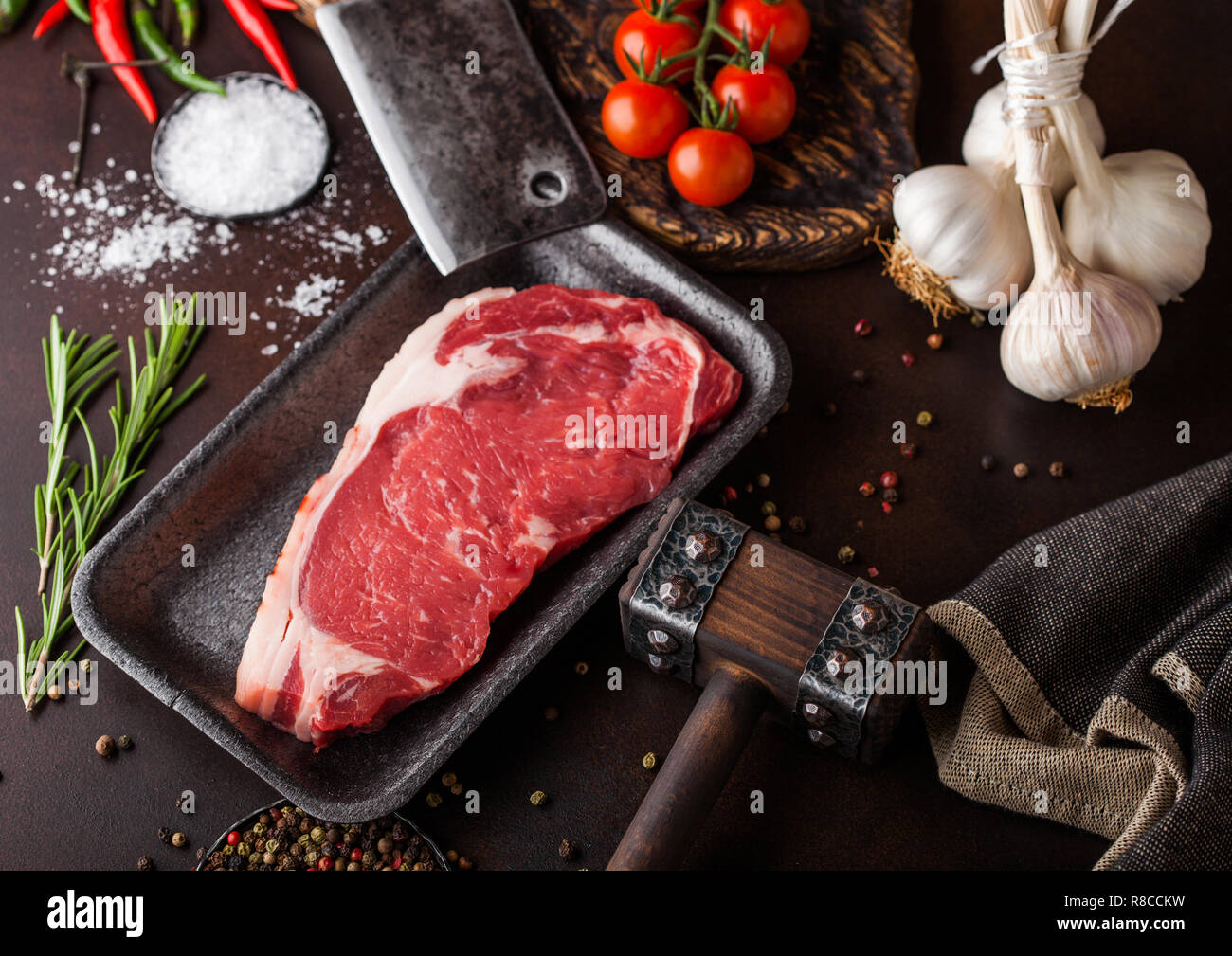 Raw sirloin beef steak in plastic tray with salt and pepper and vintage ...