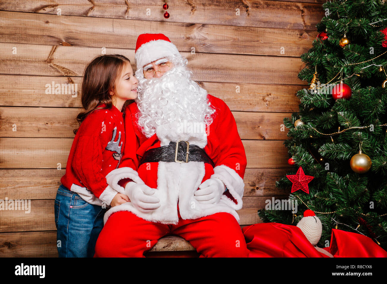 Santa Claus and Little girl. Girl telling wish in Santa Claus's ear in ...