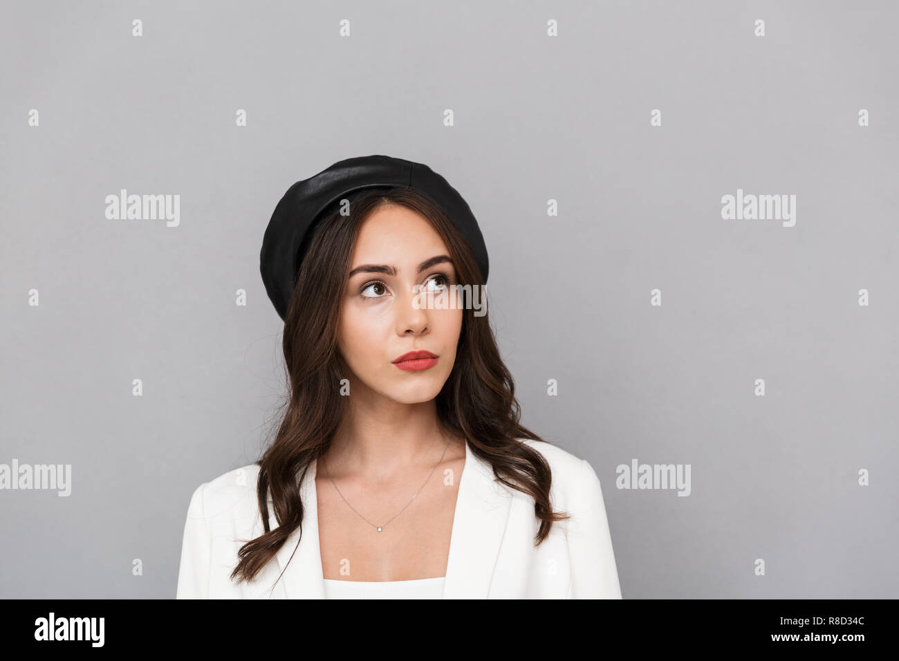 Portrait of a pretty young woman wearing beret standing isolated over ...