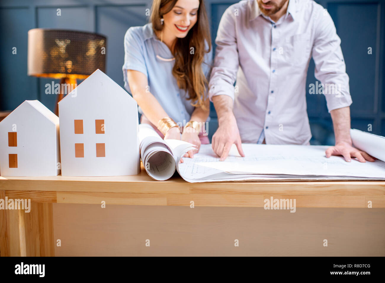 Young woman and man as an architects working with blueprints and house models in the office, close-up view Stock Photo