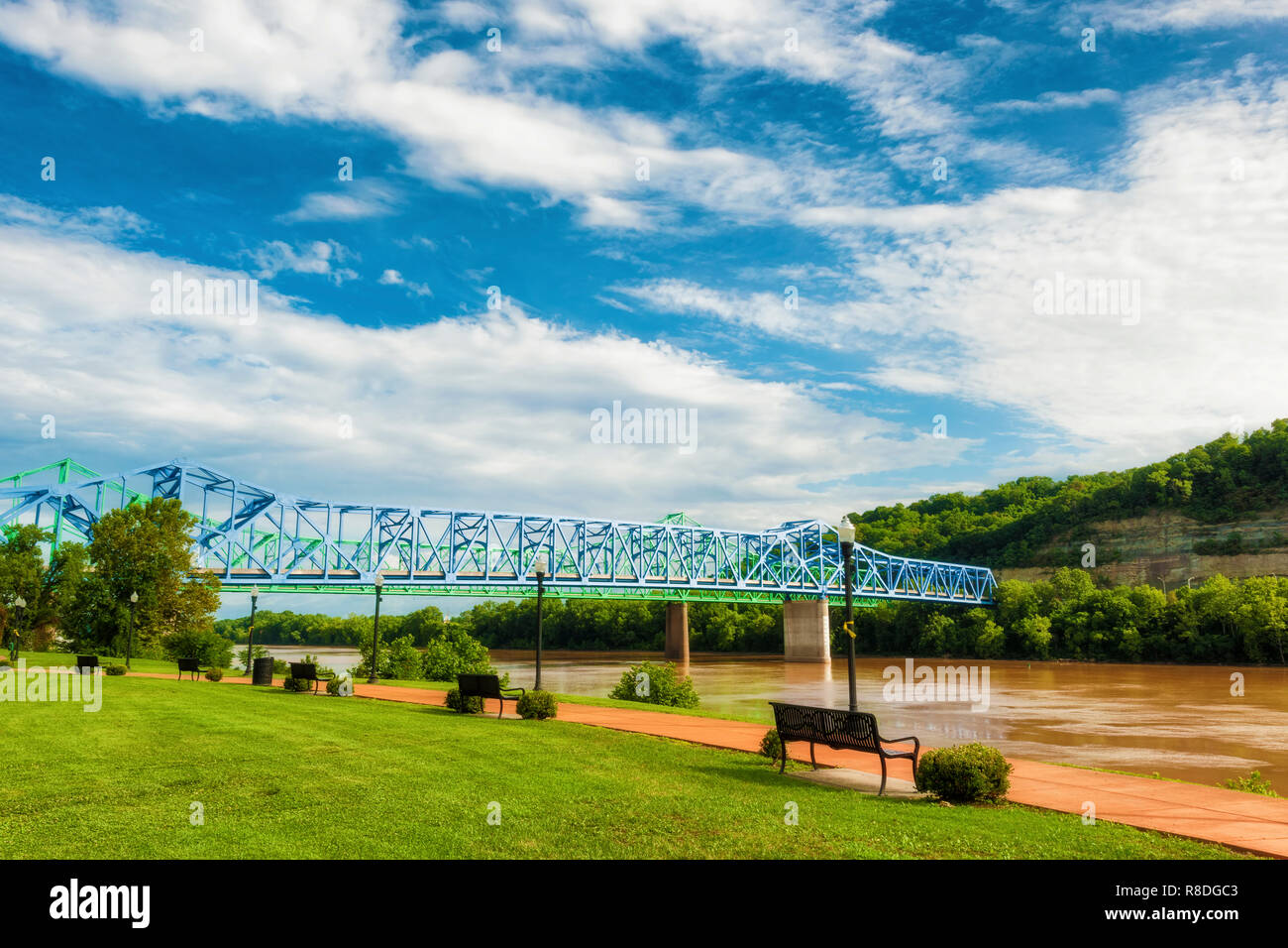 Brown waters of the Ohio River flow under two bridges along a waterfront park in Ashland, Kentucky Stock Photo