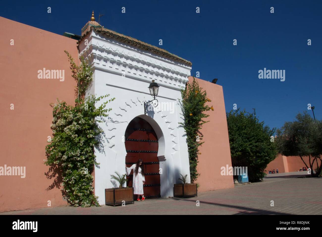 A female tourist dressed all in white poses in the doorway of a traditional Moroccan building Stock Photo