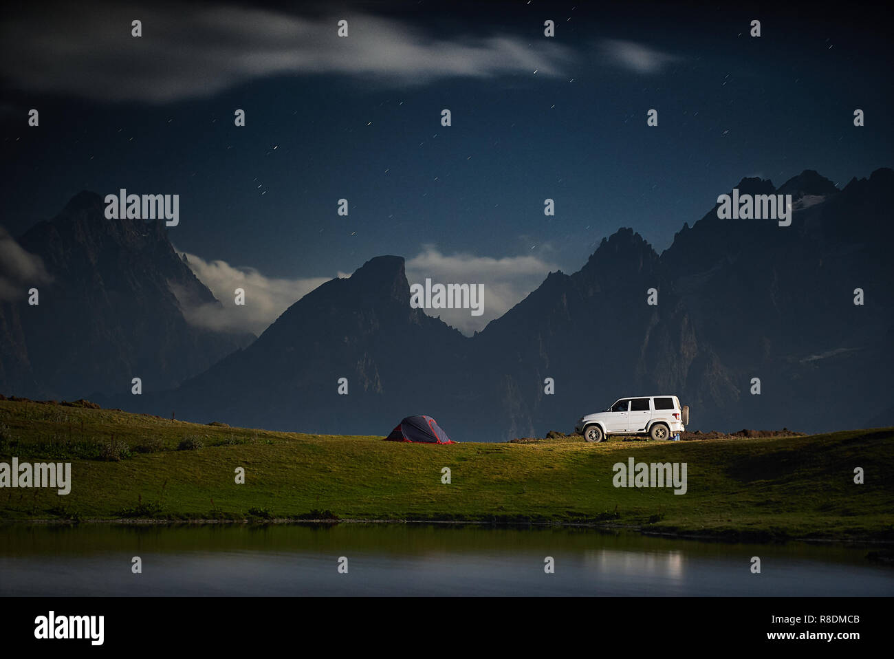 Camping with a car, tent at night with moonlight at mountain range Stock Photo