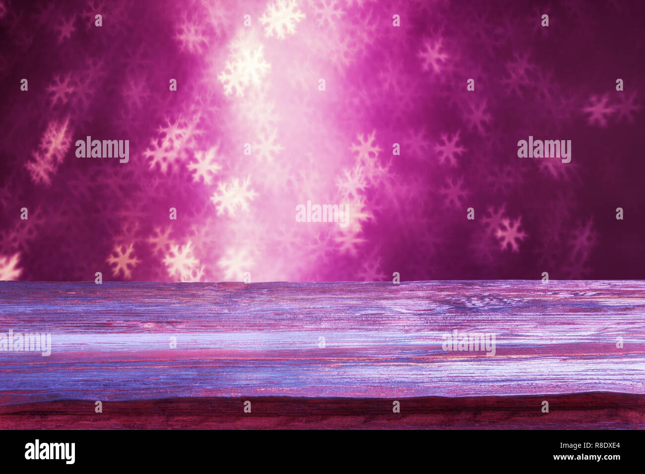 Holiday background with old wooden plank over snowflake-shaped bokeh Stock Photo