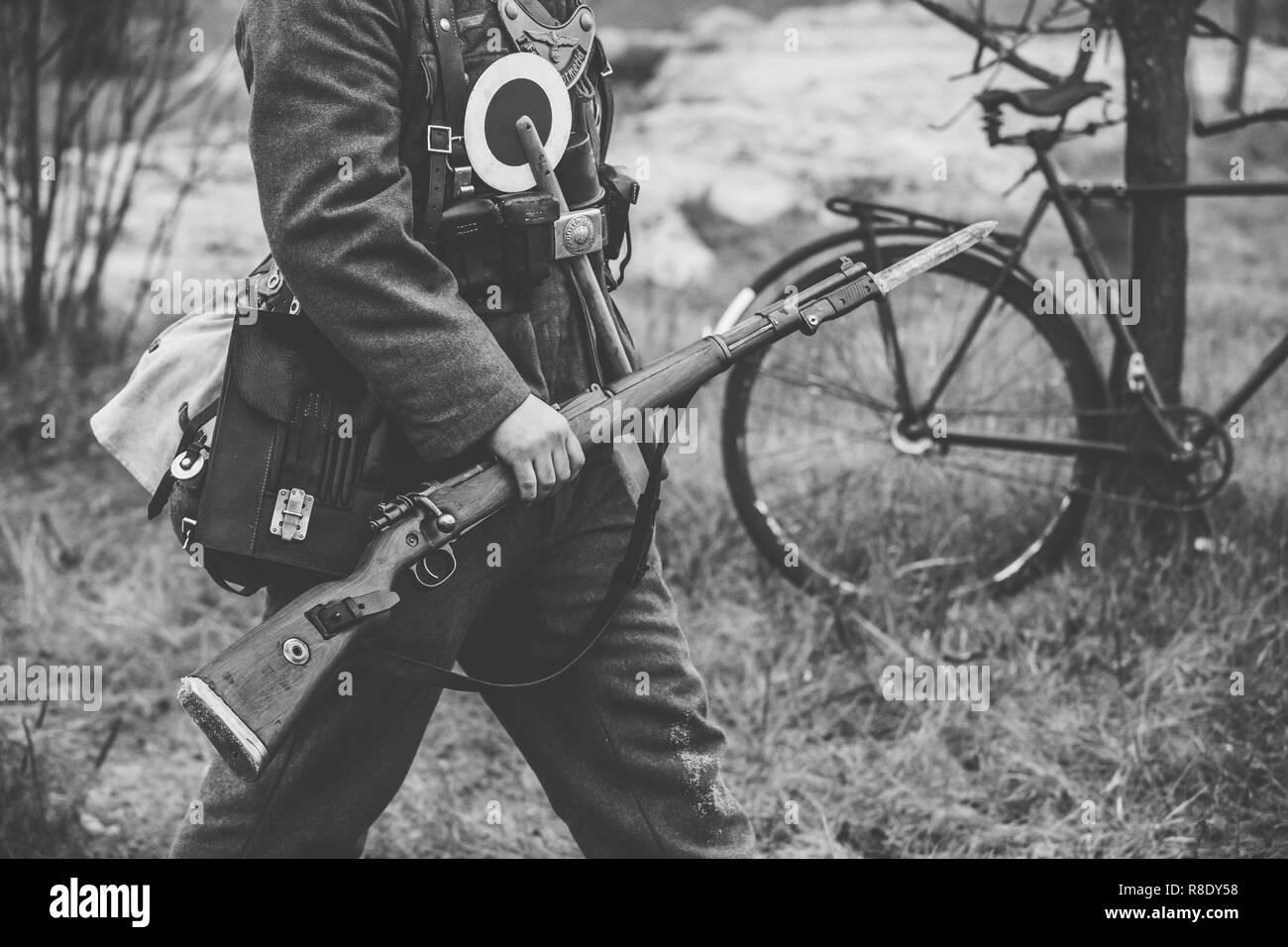 Re-enactor Dressed As World War II German Soldier Feldgendarm Holding Rifle. Photo In Black And White Colors. Soldier Holding Weapon. German Military  Stock Photo