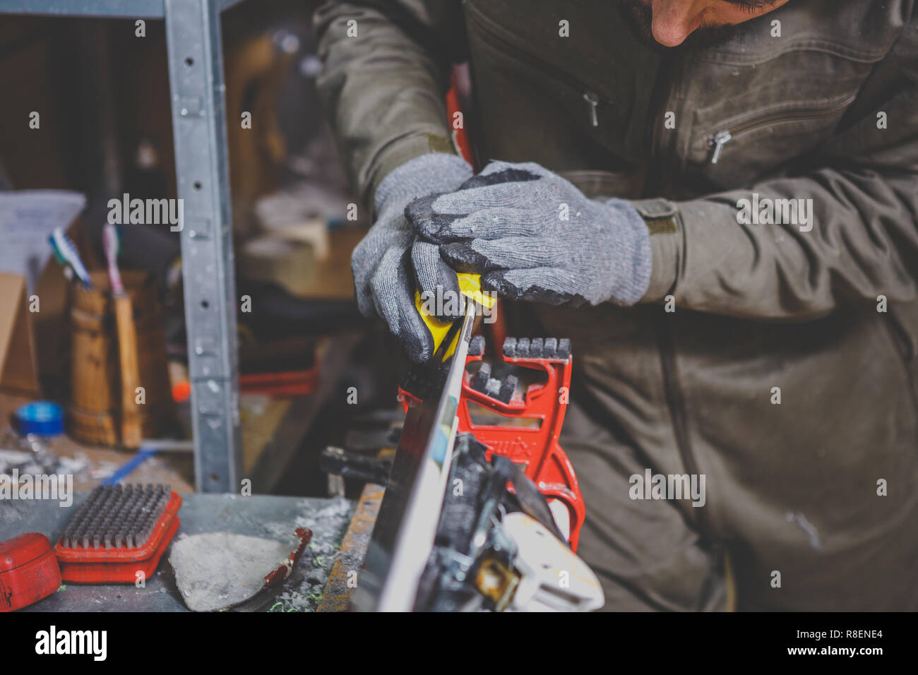 Male worker repairing Stone, edge sharpening in ski service