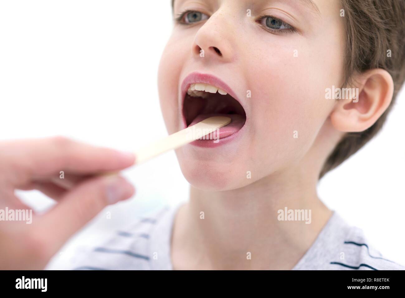 Boy with mouth open and tongue depressor. Stock Photo