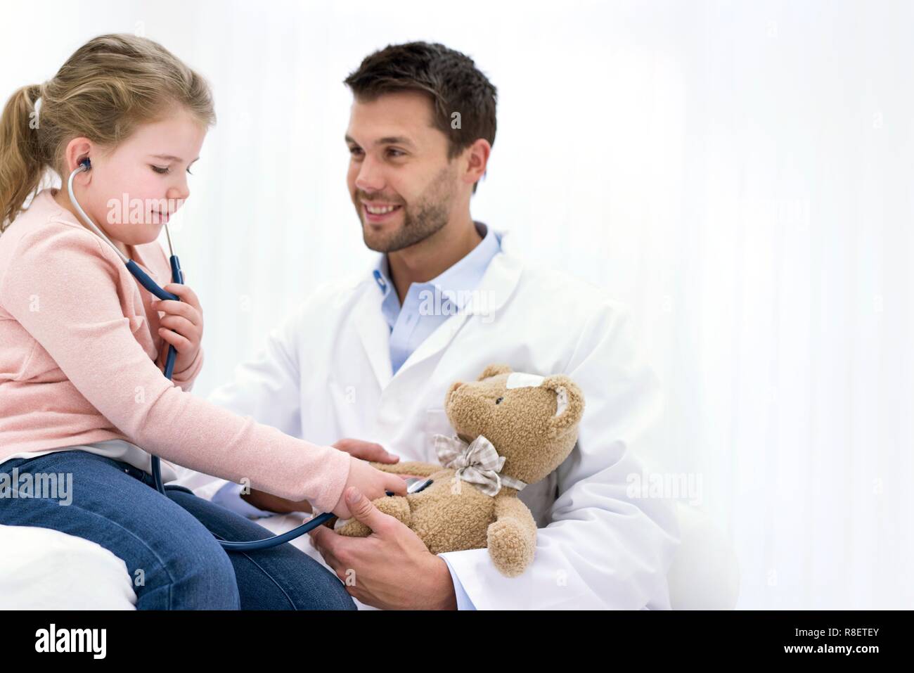 Girl playing with teddy bear and stethoscope. Stock Photo