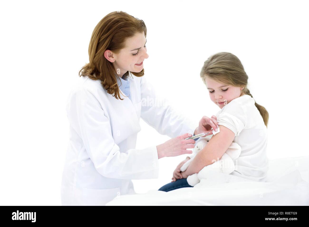 Female doctor injecting young girl in arm. Stock Photo