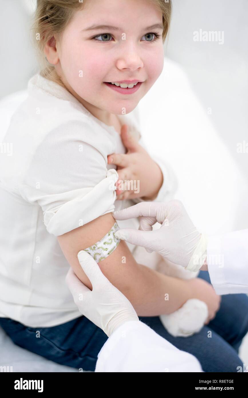 Doctor sticking plaster on young girl's arm after injection Stock Photo