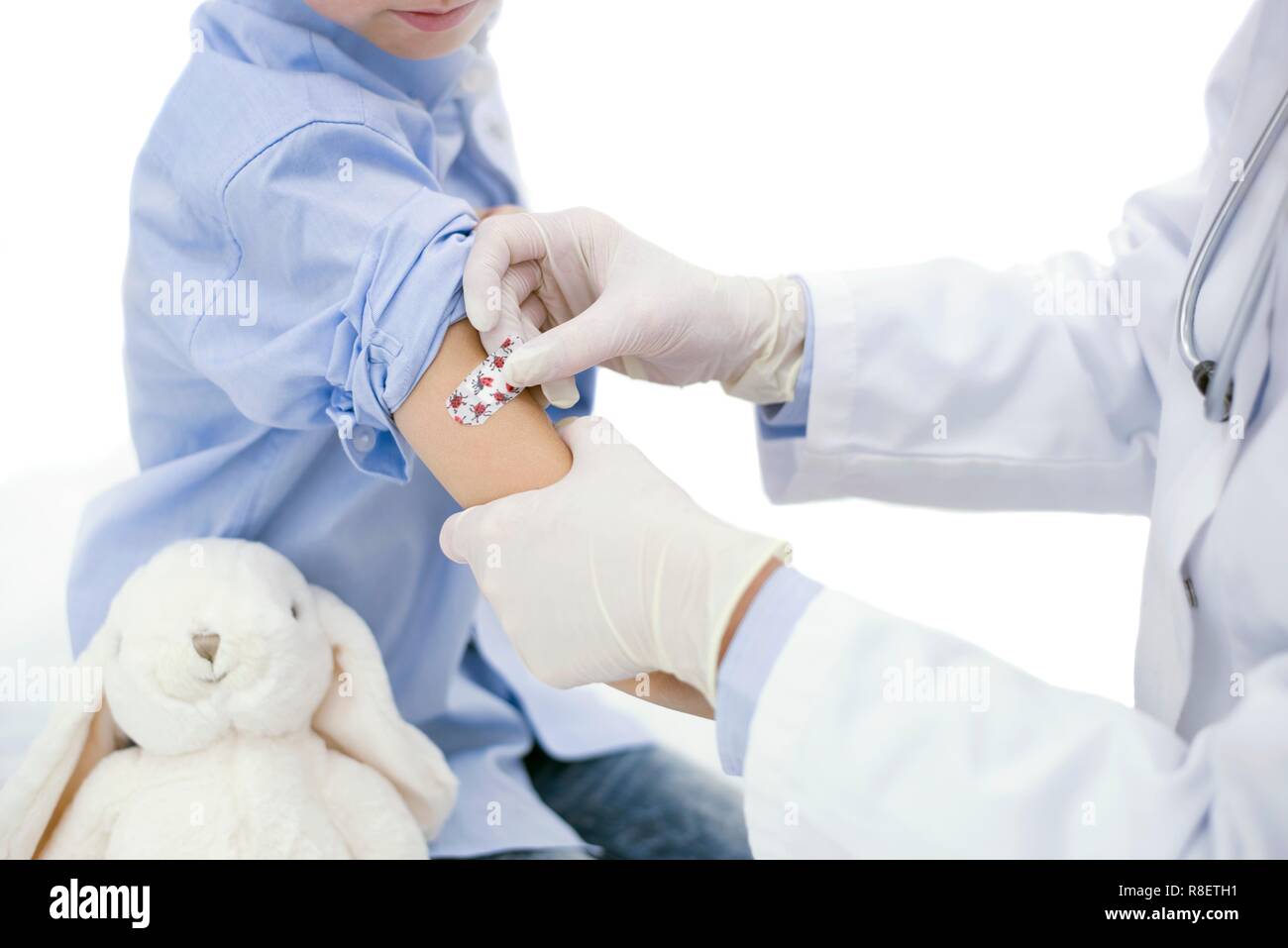 Doctor putting plaster on boy's arm after injection. Stock Photo