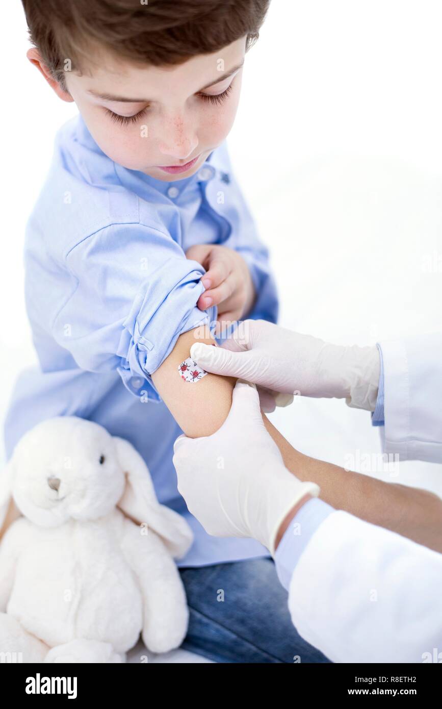 Doctor putting plaster on boy's arm. Stock Photo