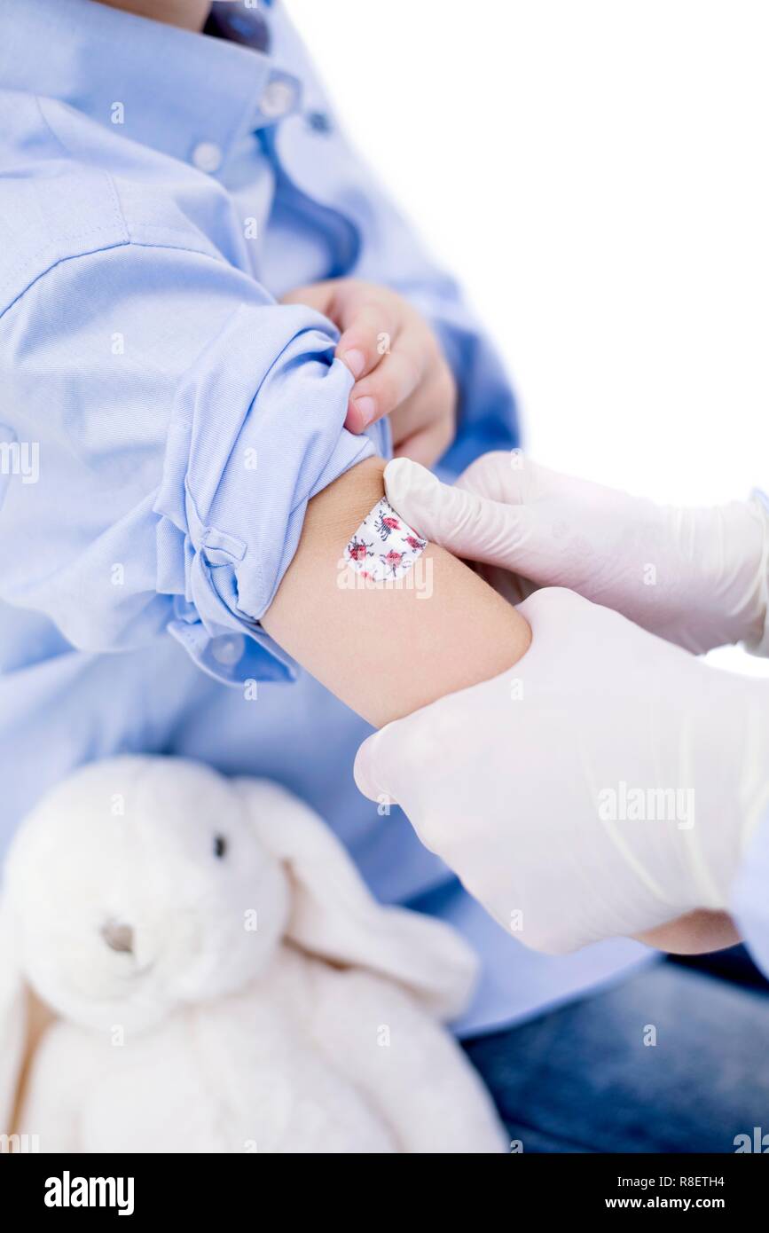 Doctor putting plaster on boy's arm after injection Stock Photo