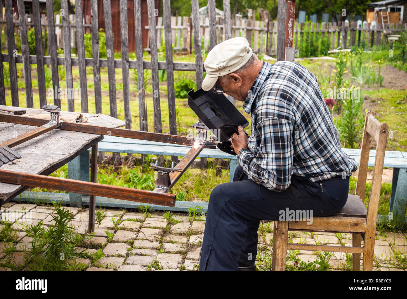 Senior man welding metal structure at his garden Stock Photo