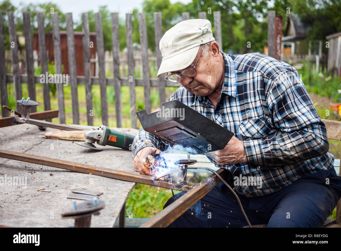 Senior man welding metal construction at his garden Stock Photo