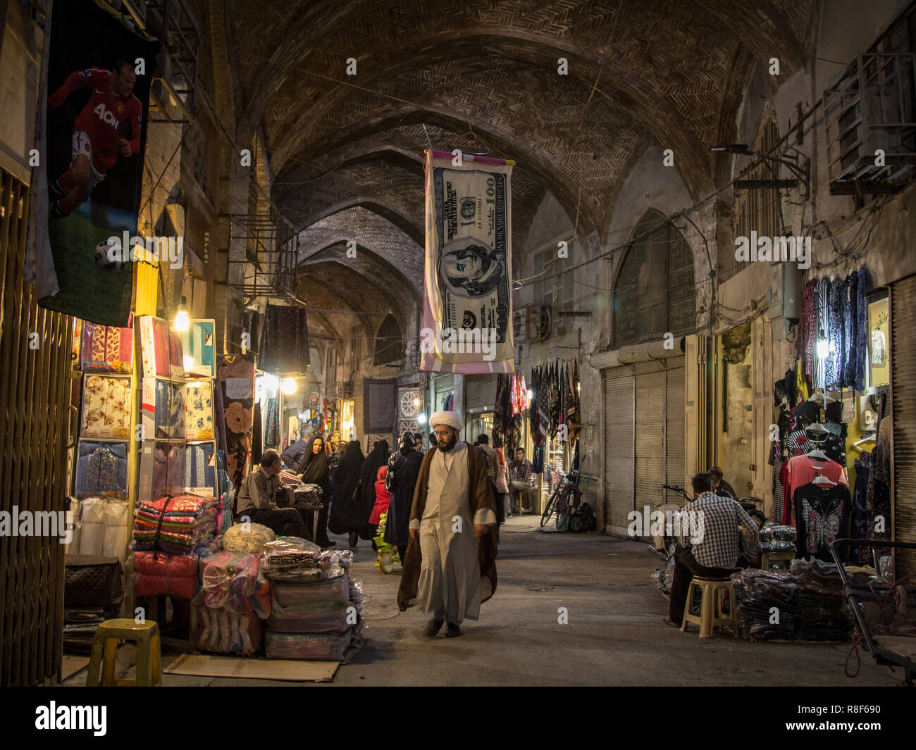 ISFAHAN, IRAN - AUGUST 20, 2018: Islam passing under a towel shaped like a US Dollar bill in the Isfahan bazar in the evening. The iranian rial, iran  Stock Photo