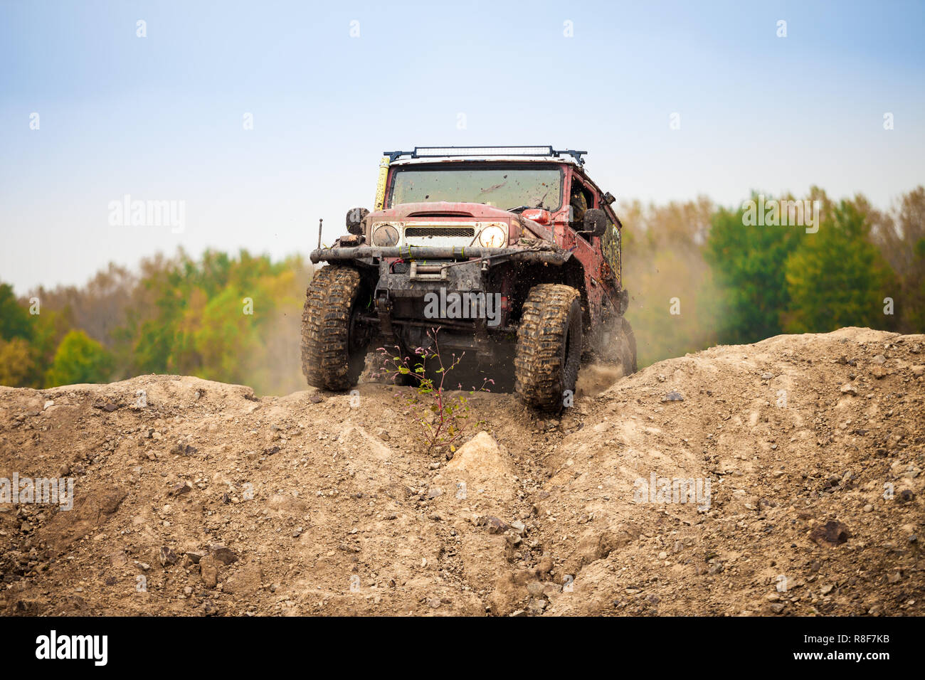 Classic red off road car moving on dirt terrain Stock Photo
