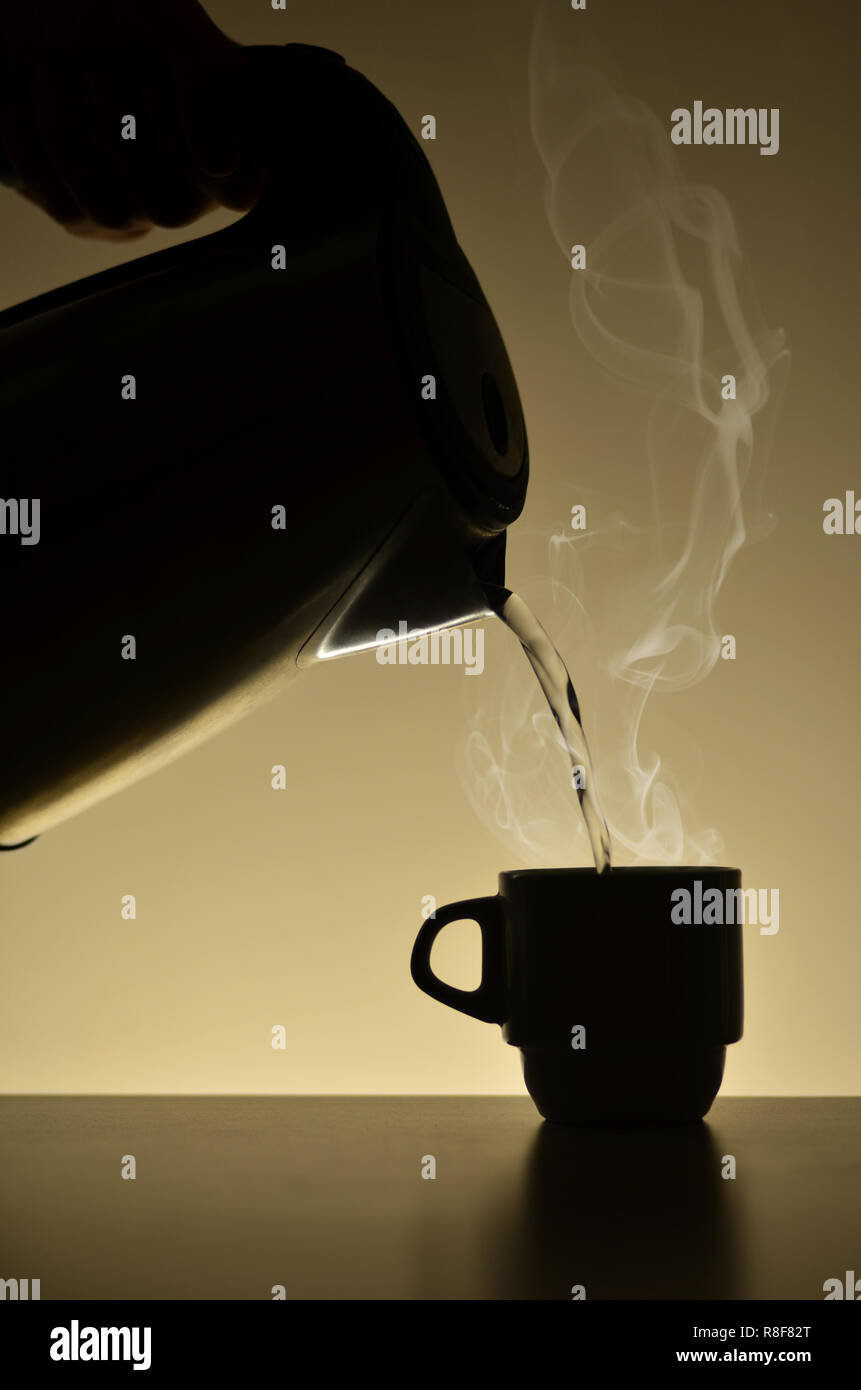 Fill the coffee cup with hot water from the electro kettle Stock Photo