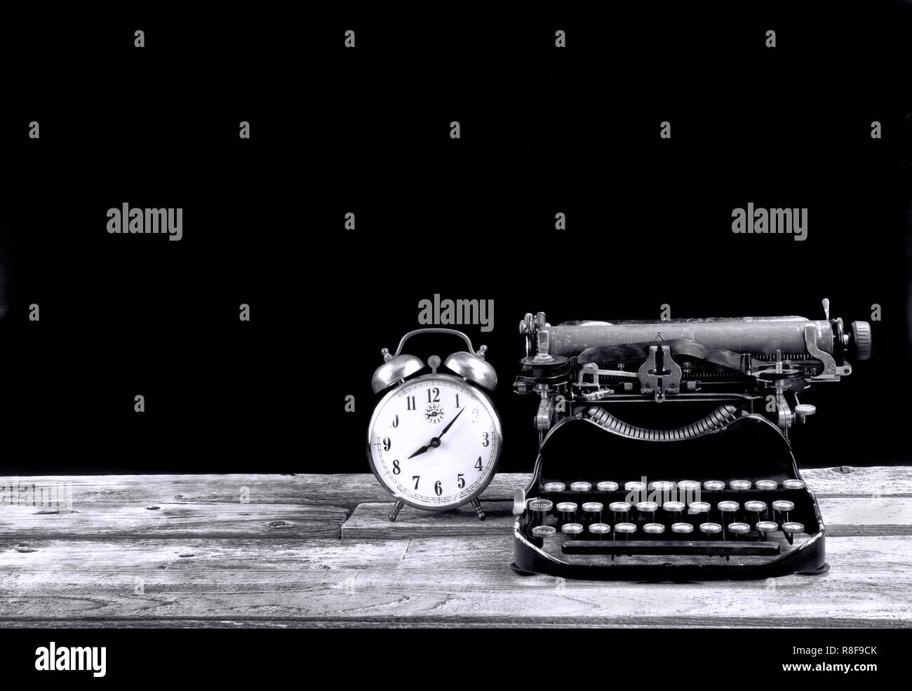 Antique portable typewritter and alarm clock made in 1917 with room for your type in black and white. Stock Photo