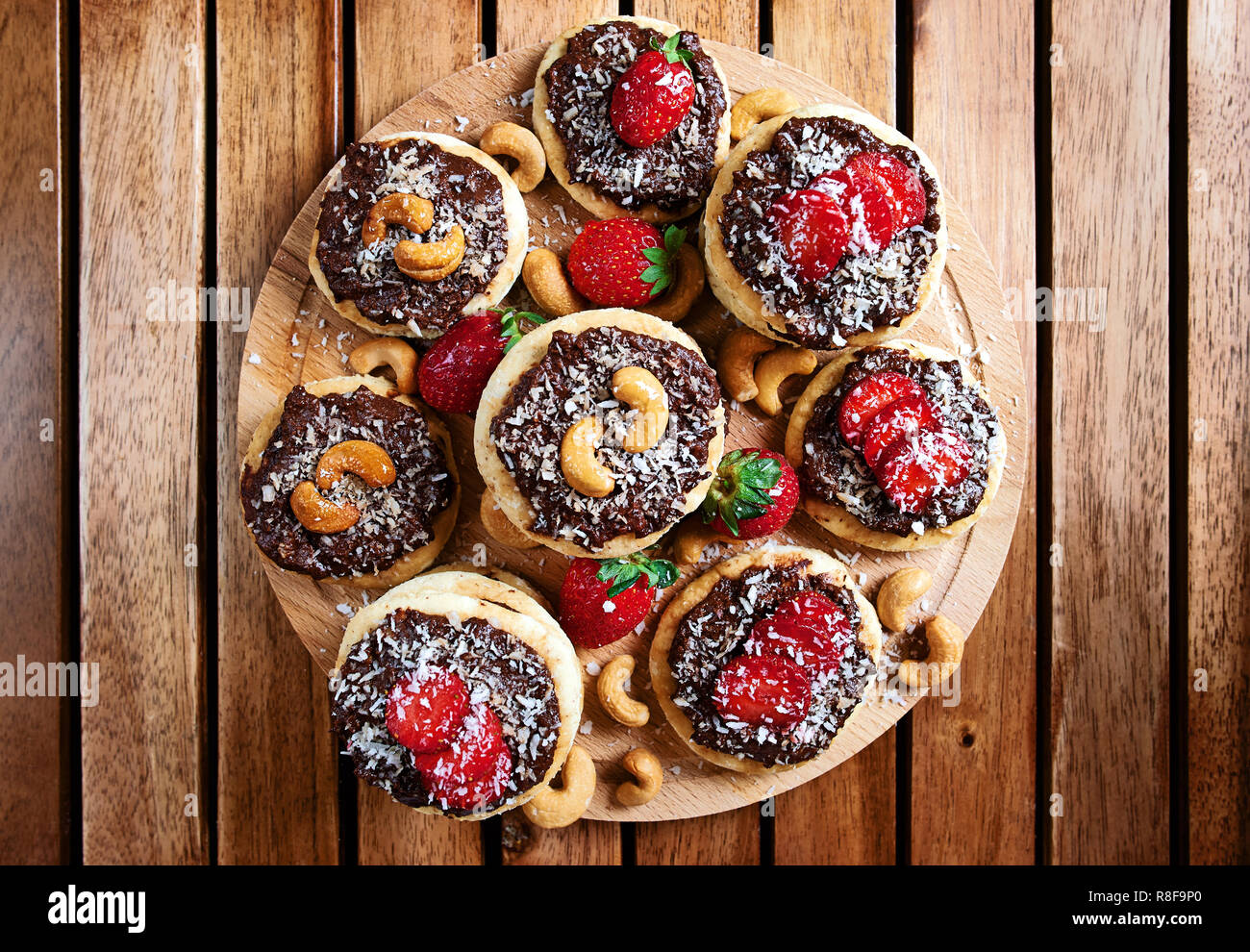 vegan homemade coconut cookies with strawberries and chocolate nut toping, top view Stock Photo