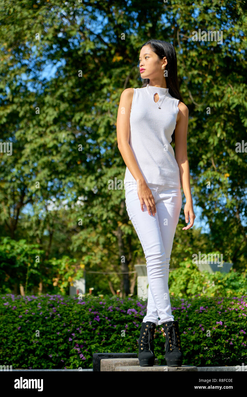 Beautiful woman posing standing, cross legged and looking away Stock