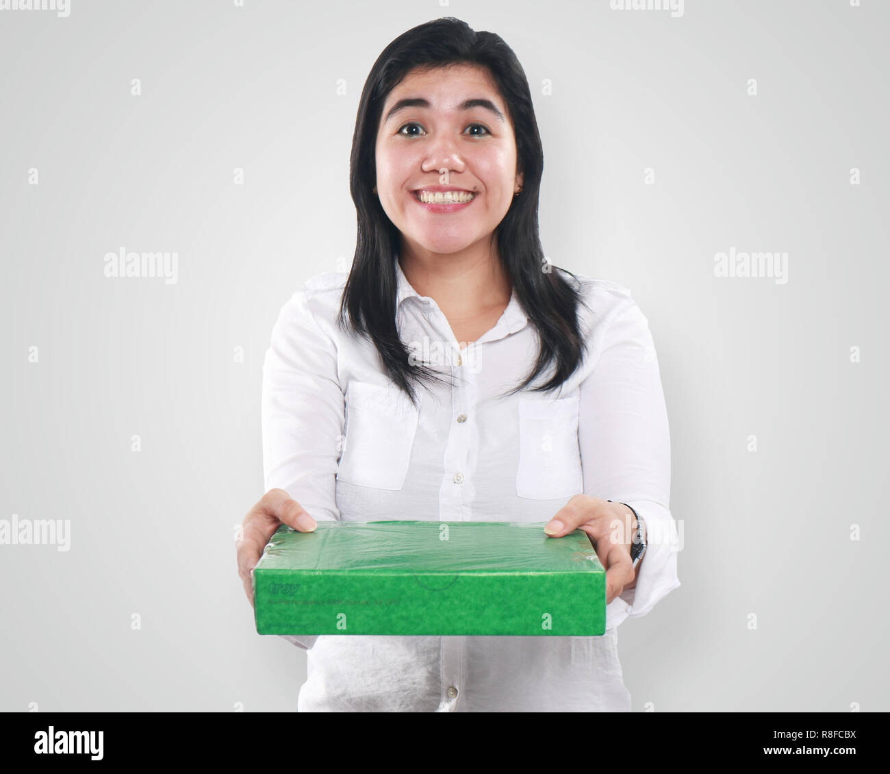 Photo image portrait of a young beautiful Asian woman smiling while giving green gift package box, close up portrait over white background Stock Photo