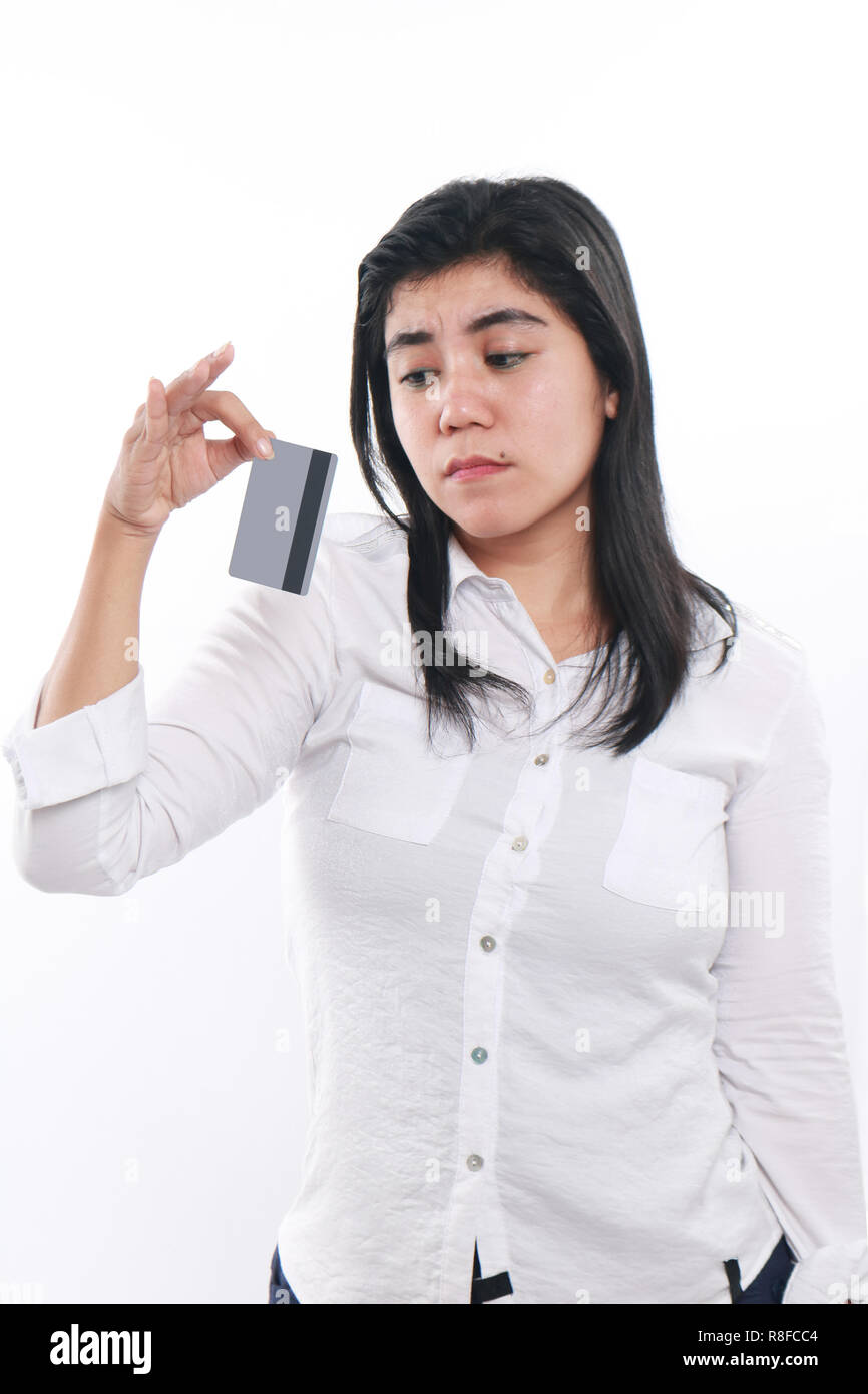 Photo image portrait of a sad Asian woman while looking to her credit card, economic depression, bankruptcy concept, close up portrait over white Stock Photo