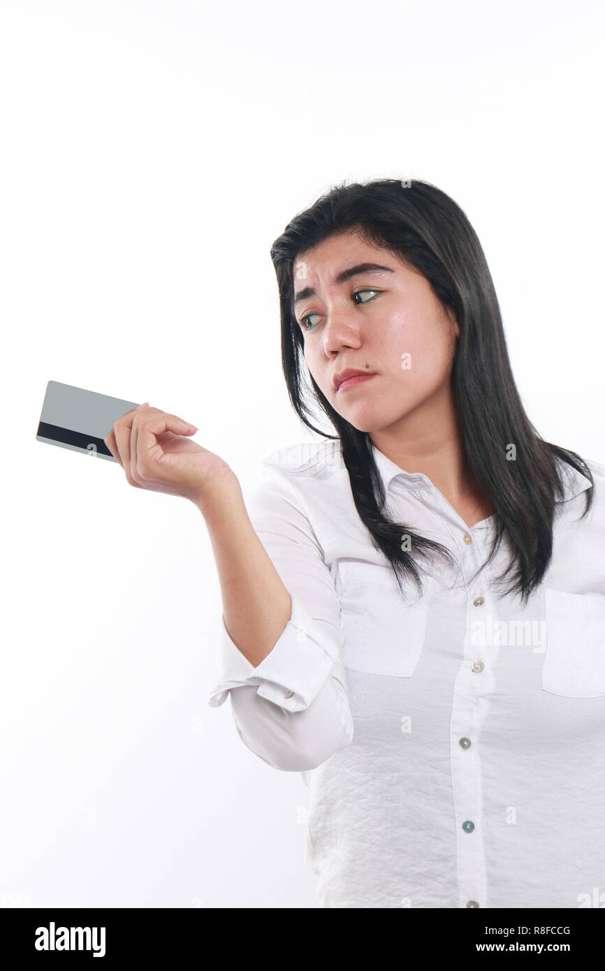 Photo image portrait of a sad Asian woman while looking to her credit card, economic depression, bankruptcy concept, close up portrait over white Stock Photo