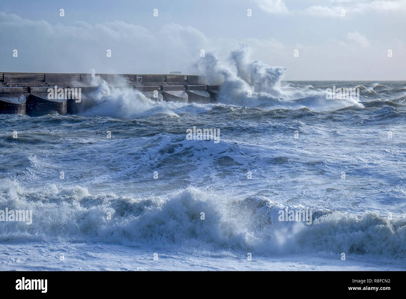 Dramatic stormy sea breaking against Brighton marina black stone harbour wall, spray and waves high in the air, rough sea, Brighton, East sussex, Uk Stock Photo