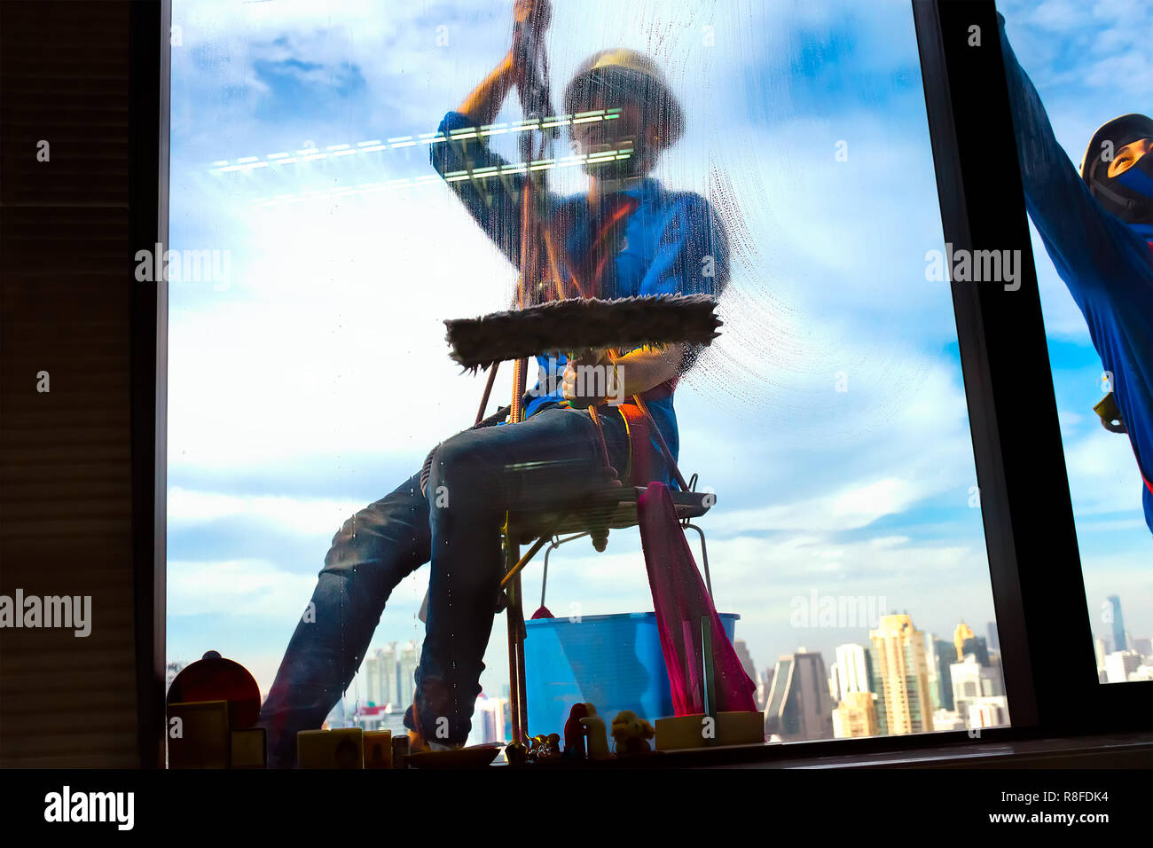 Two window cleaners hanging on ropes, cleaning the windows of a high rise building. Stock Photo