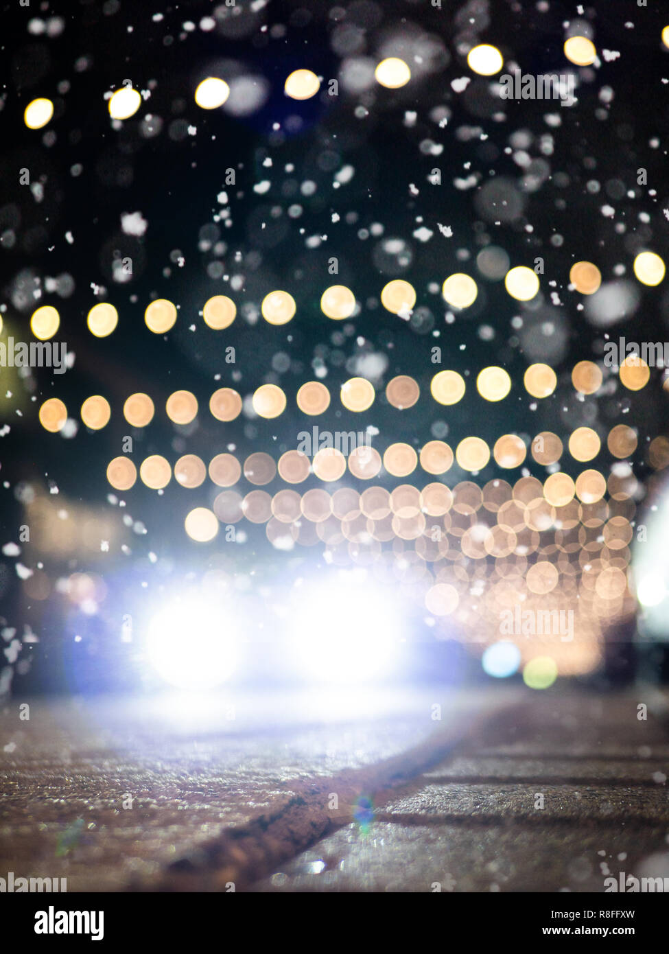 Slippery streets: Defocused car driving on snowy street with christmas decoration, snow falling Stock Photo
