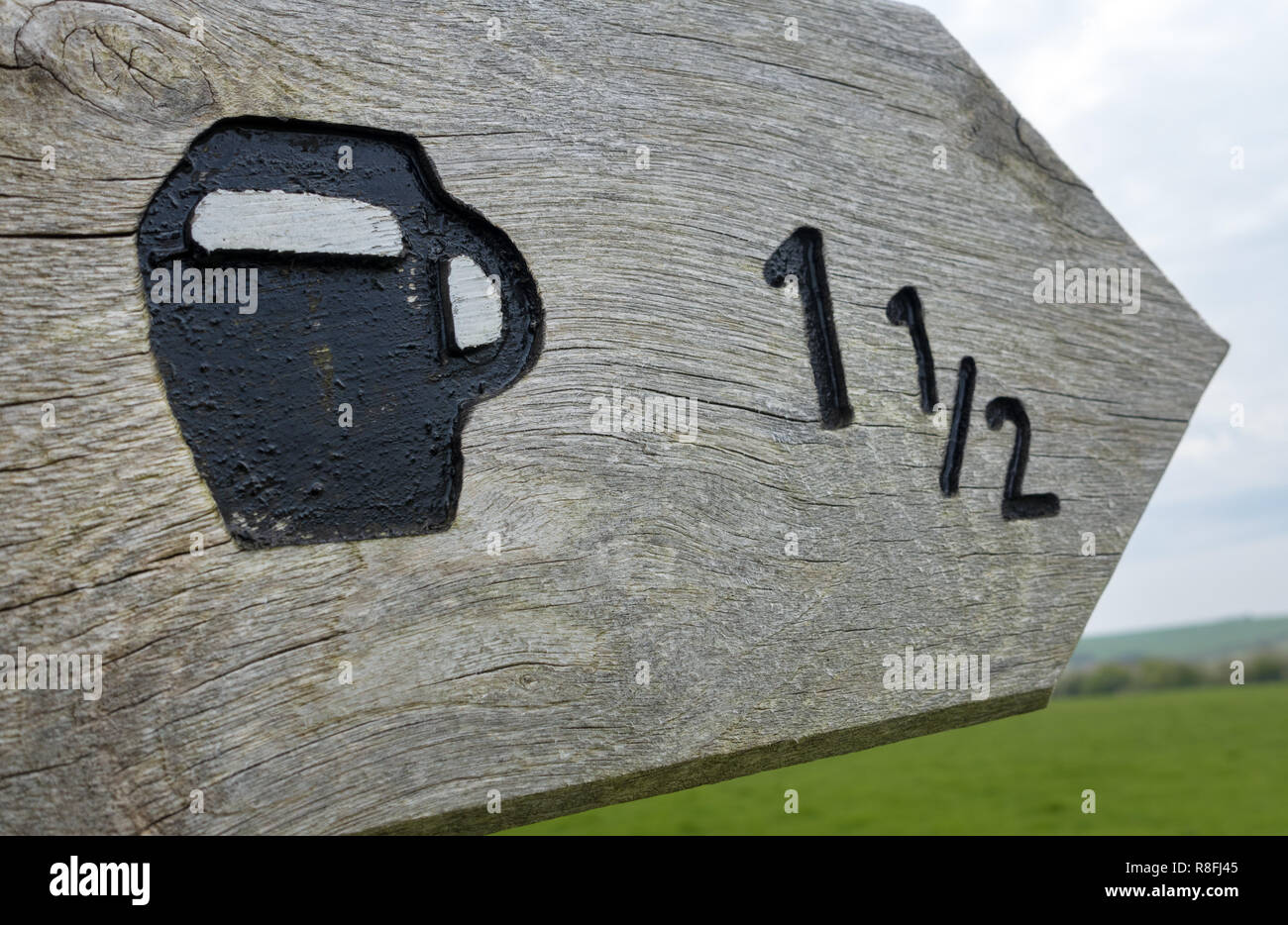 Wooden signpost giving directions to the pub on the Purbeck Way in Dorset, England, UK Stock Photo