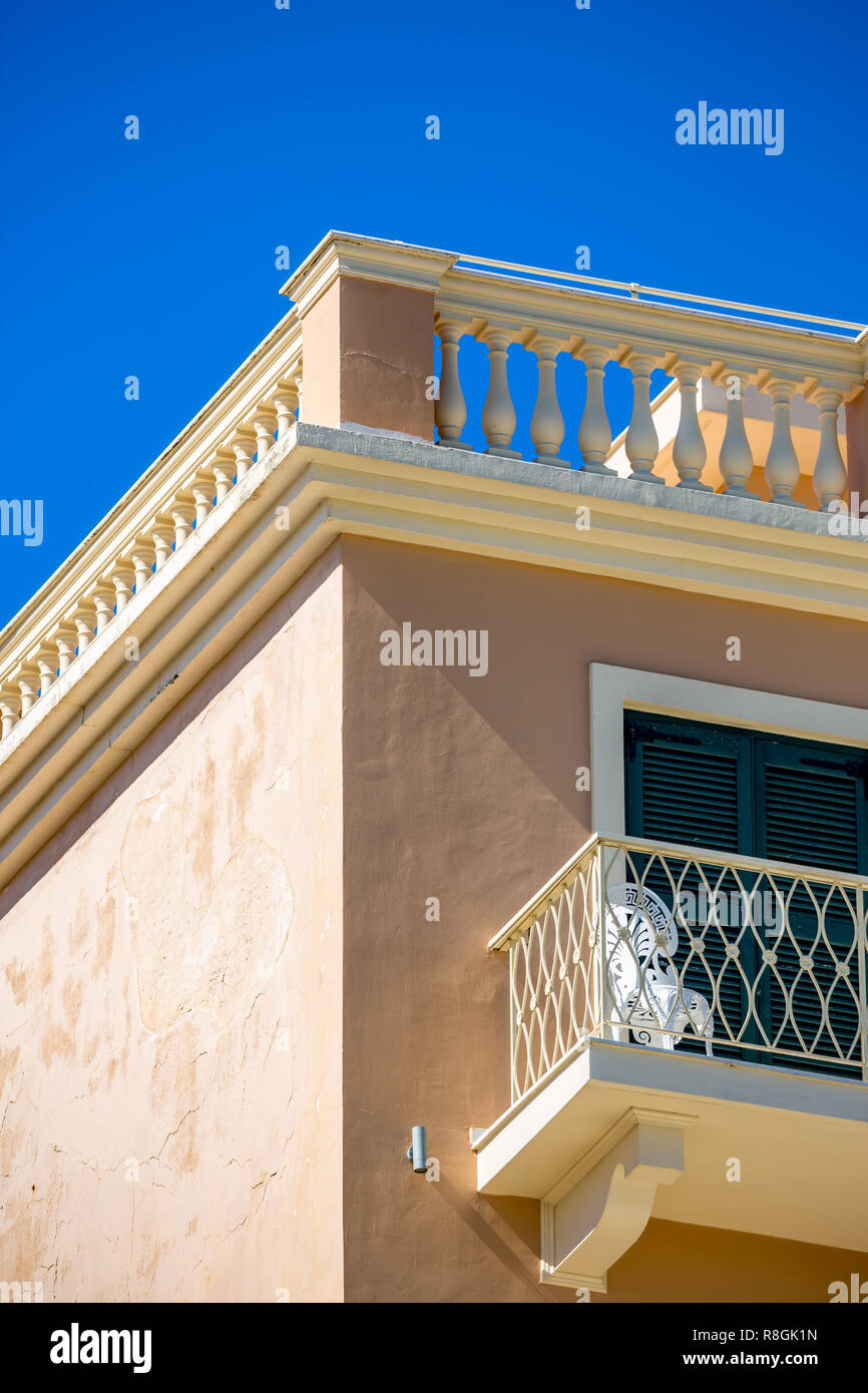 Pale Mediterranean building corner with balcony, lit by the Sun in