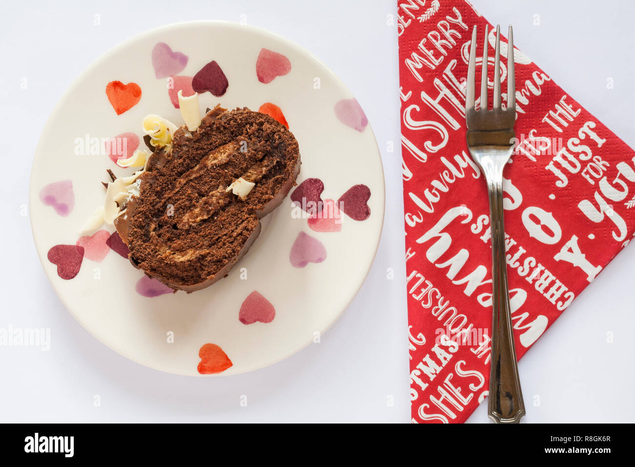 Slice of M&S Yuletide Log on plate with fork on Christmas serviette napkin - from above looking down on Stock Photo