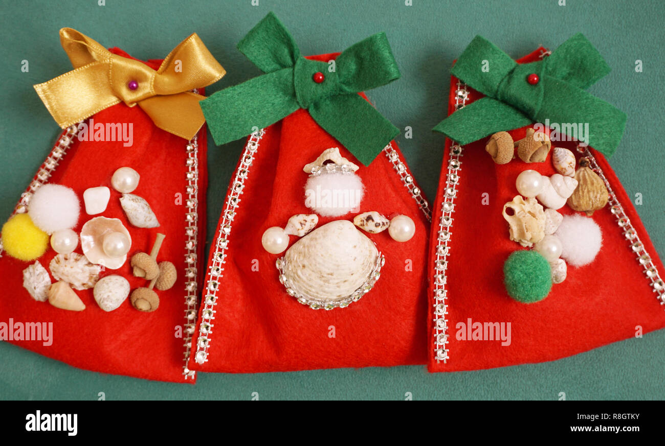 Christmas crafts concept. Do it yourself handmade felt gift bags decorated with seashells and beads Stock Photo