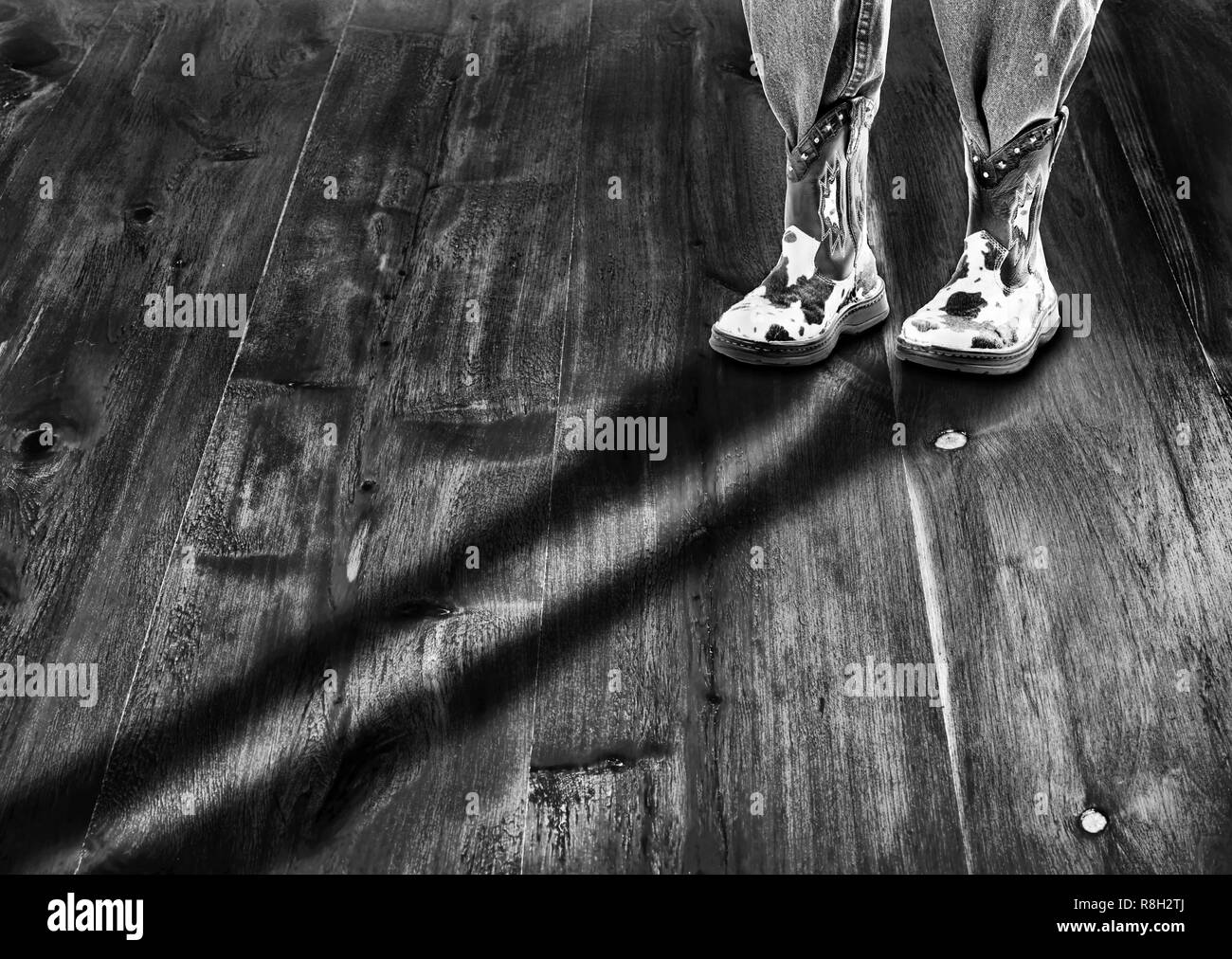Cowboy boots with log shadow and room for your type in moody black and white.. Stock Photo