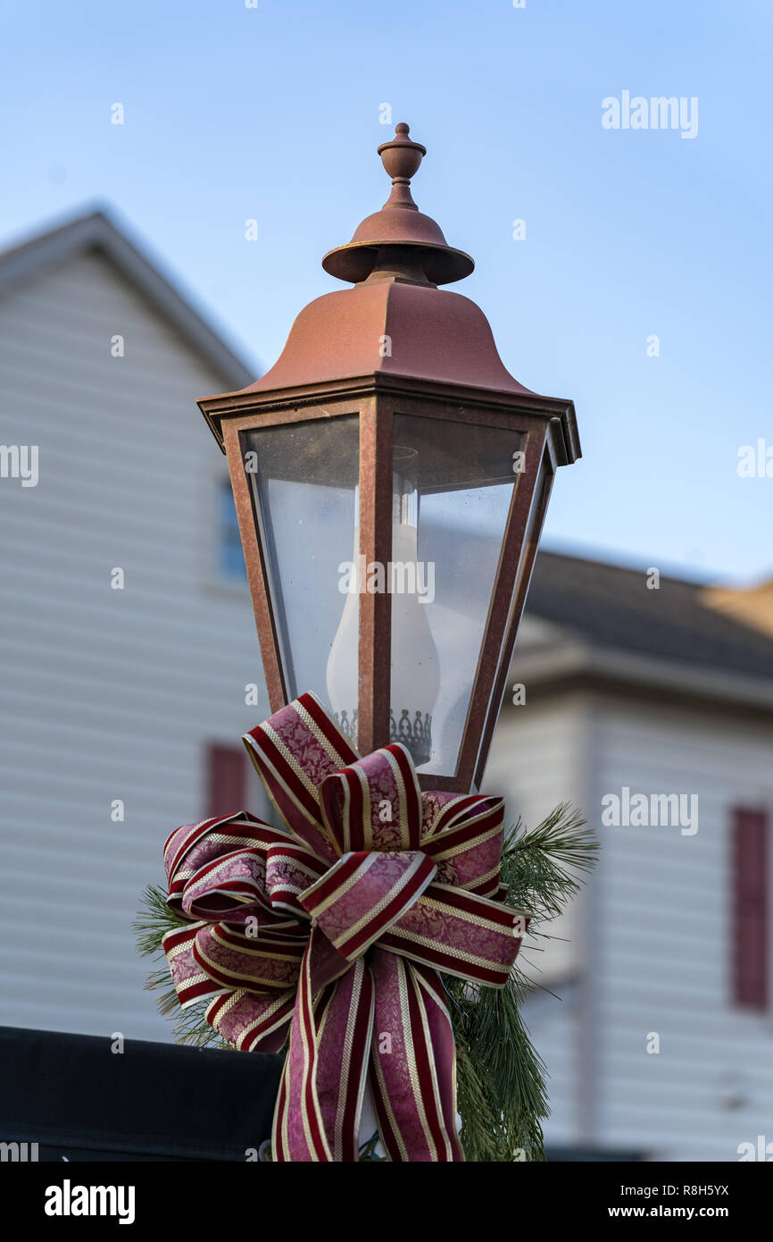 An electric street lamp decorated for the Christmas holiday with a seasonal bow ribbon. Stock Photo