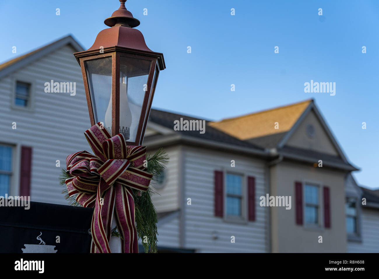 An electric street lamp decorated for the Christmas holiday with a seasonal bow ribbon. Stock Photo