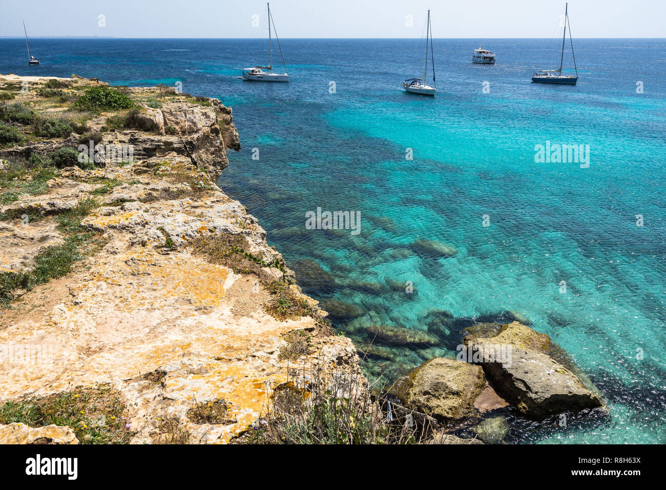 Crystal Clear Waters And Sailboats At Cala Azzurra, One Of The Most 