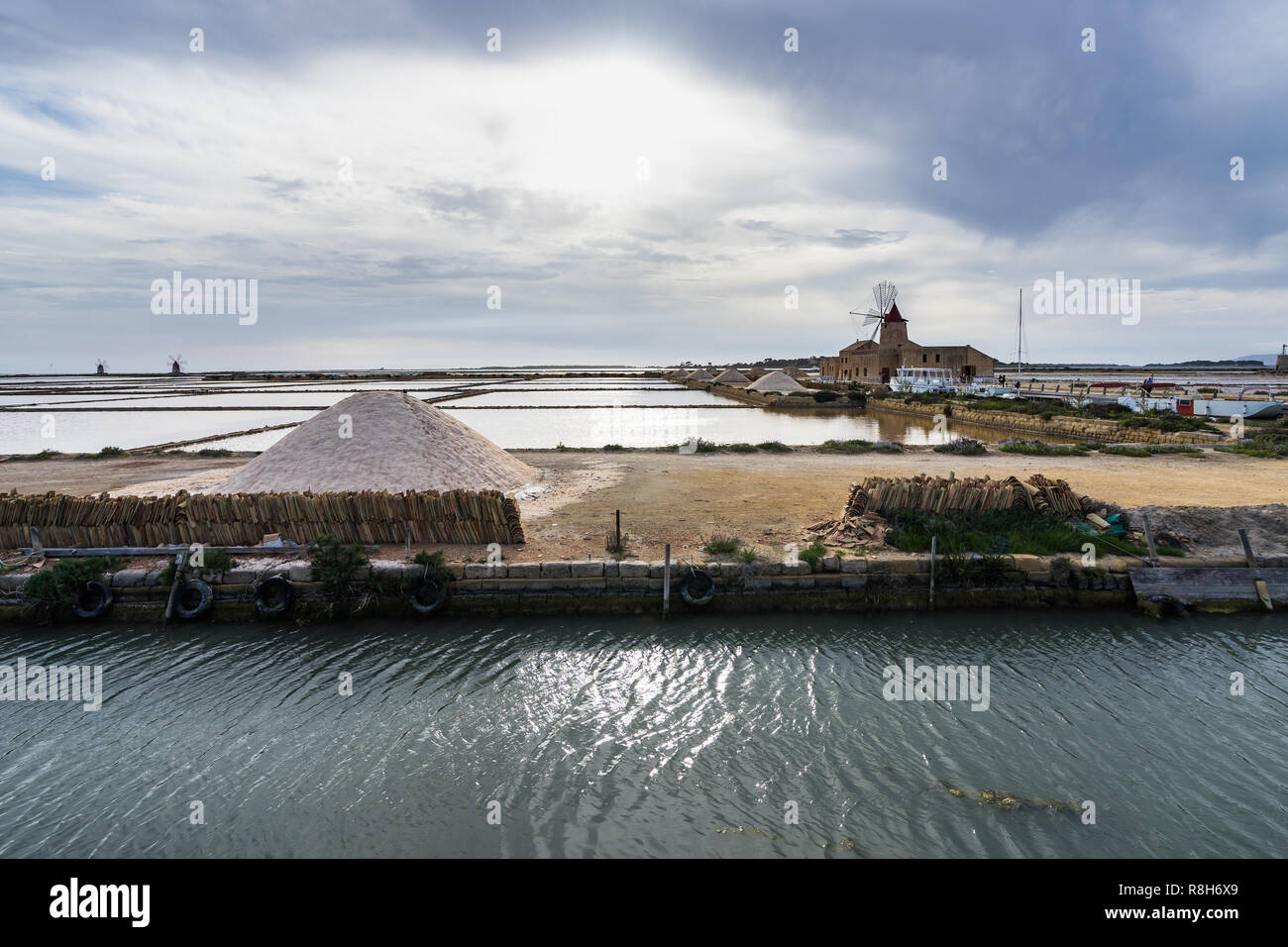 Natural reserve “Saline dello Stagnone” with salt evaporation pond and the old windmill in the background, Marsala, Sicily, Italy Stock Photo