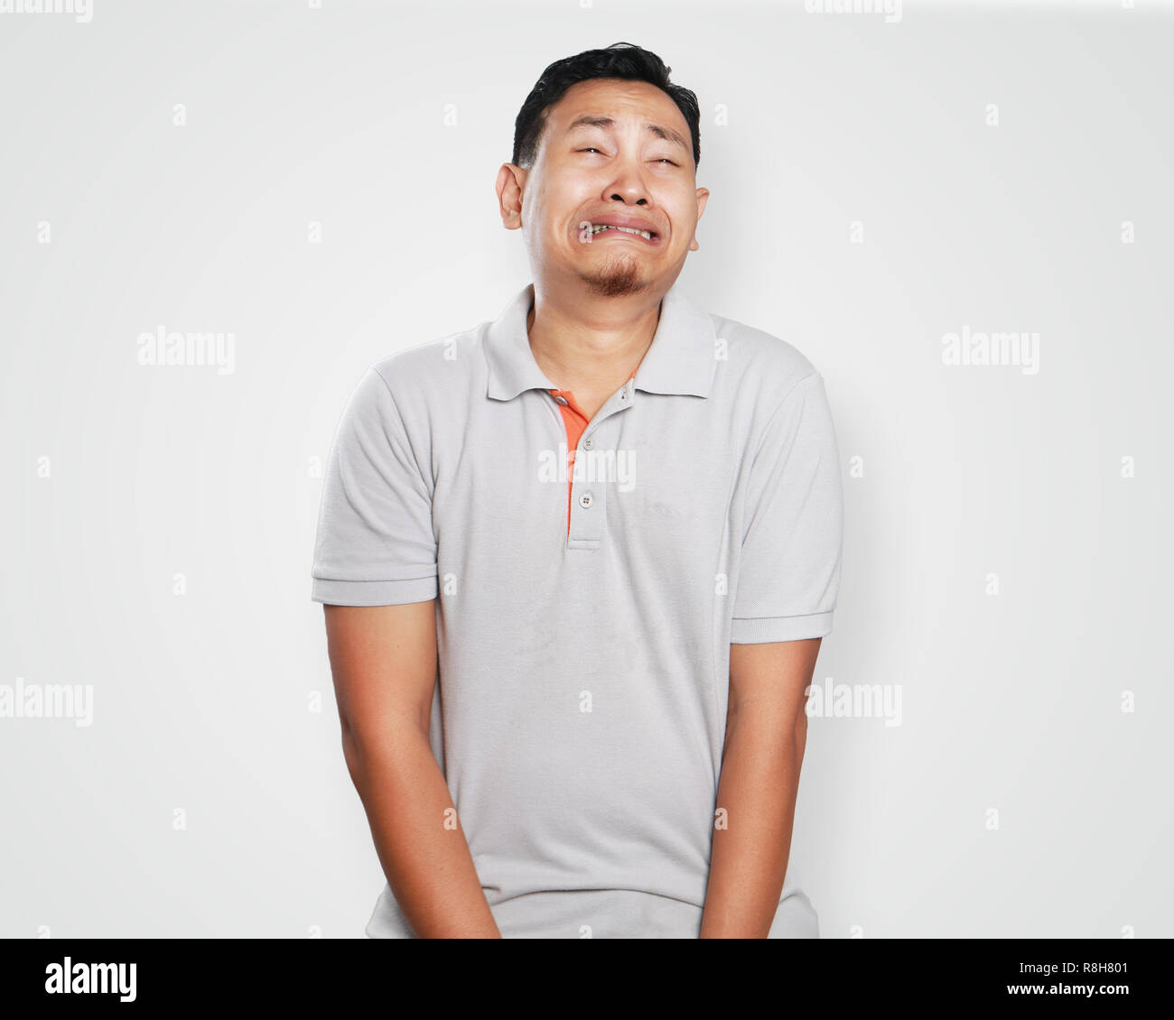 Photo image portrait of a cute handsome young Asian man crying hard, painful in his sensitive area gesture Stock Photo